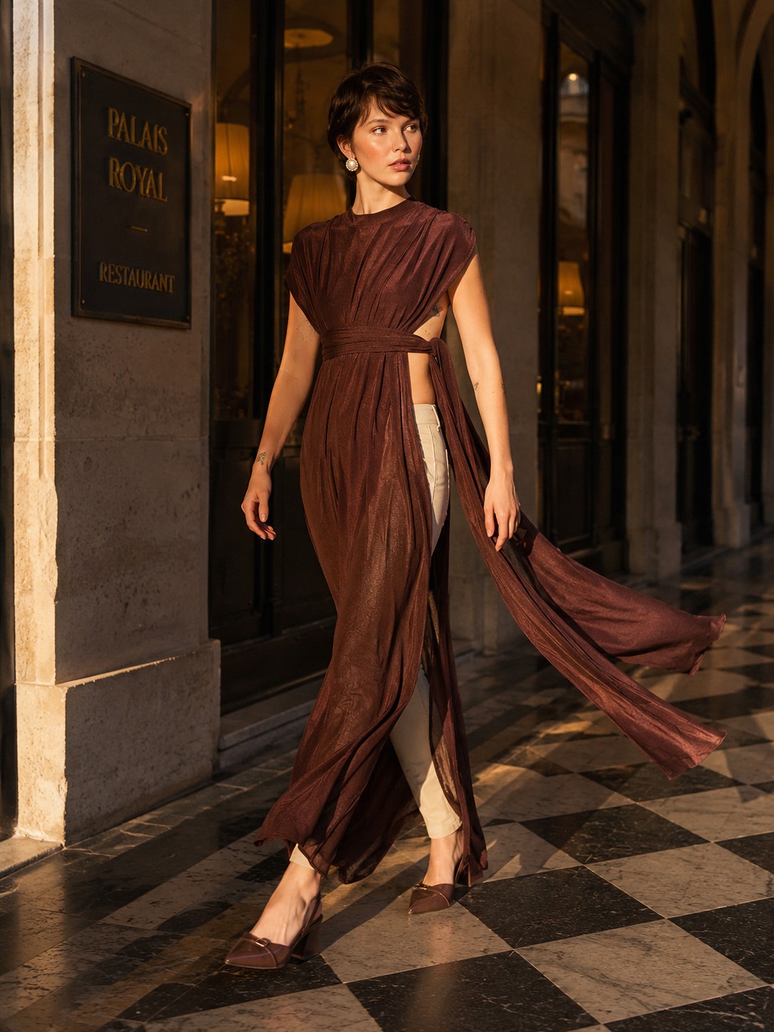 Modelo com blusa jersey longa drapeada marrom da Coleção Lumière – Branca Boutique em frente ao Palais Royal