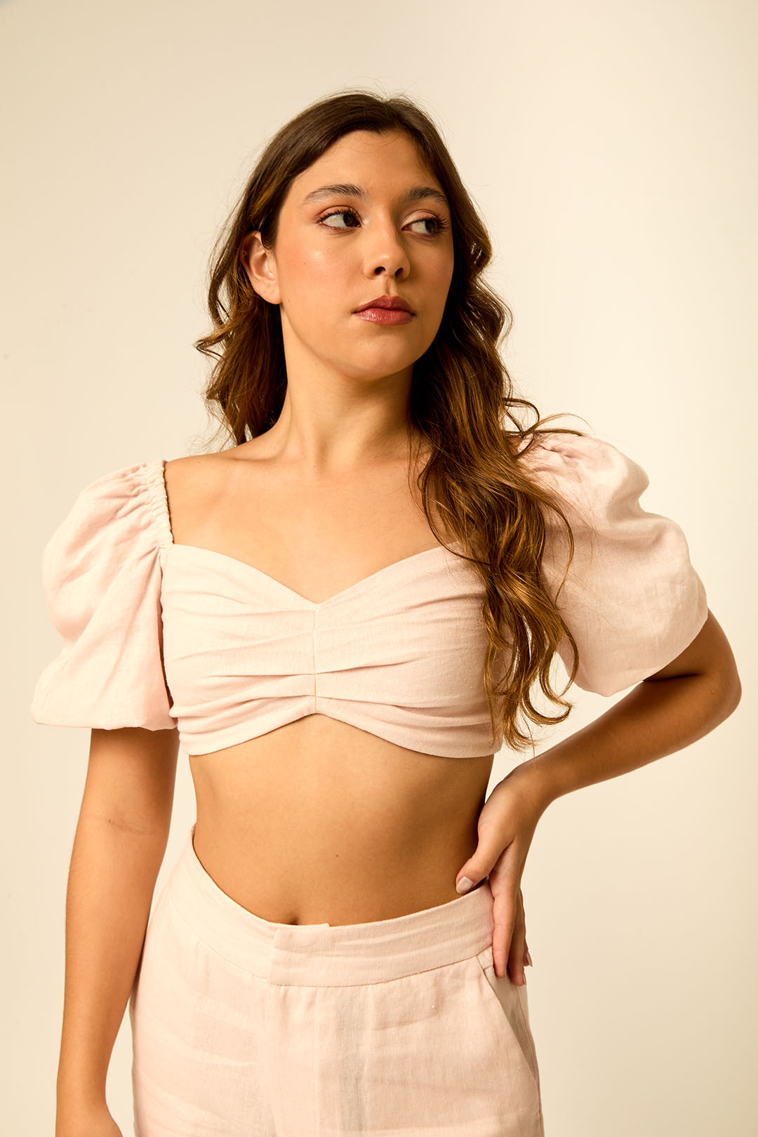 Modelo usando conjunto de linho rosa bebê: cropped de manga bufante com busto franzido e calca de cintura alta da Branca Boutique