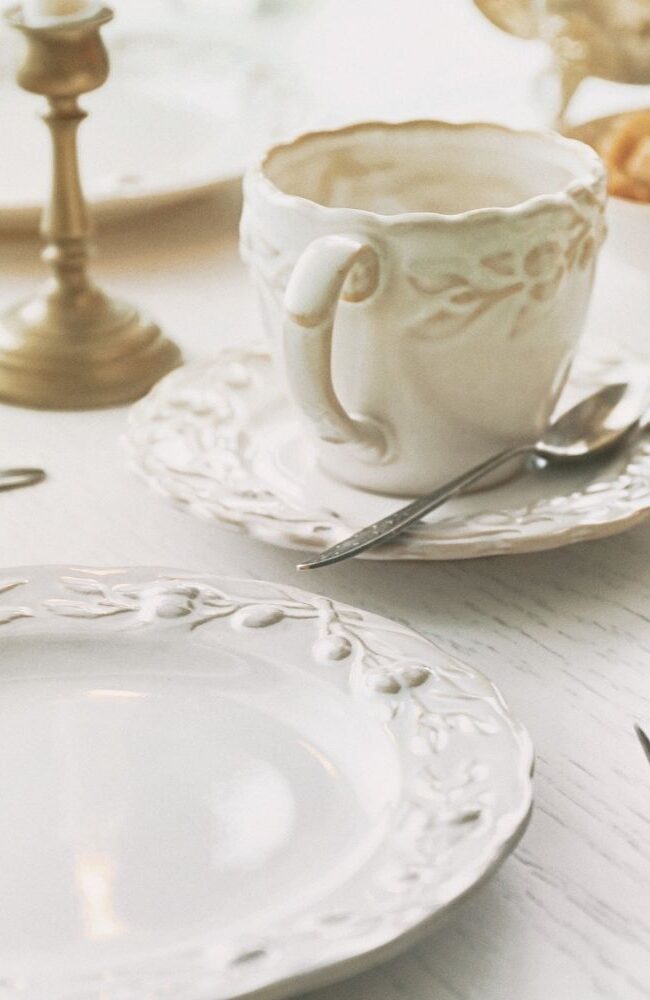 Talheres elegantes e louças de porcelana branca sobre mesa com castiçais de bronze – arte de receber com requinte